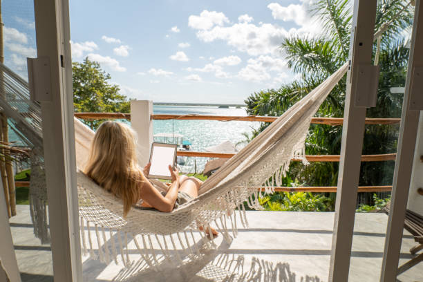 istock Young woman relaxing in an hammock on her balcony using her digital tablet 1369775520