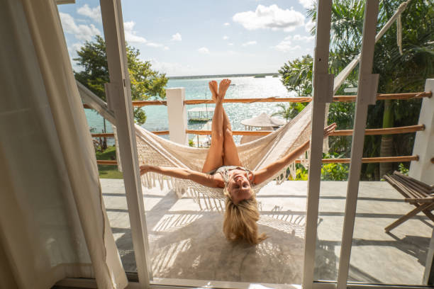 Woman relaxing in an hammock on her balcony, lake and garden view stock photo