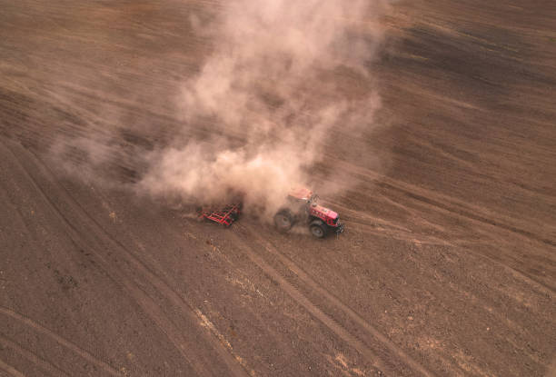 istock Tractor with plough on field cultivating. Field cultivating, aerial view. Tractor with disk harrow on plowed. 1369777421