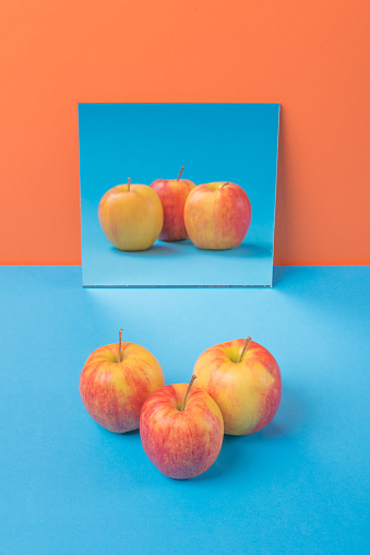 Image of apple on blue table isolated over orange background