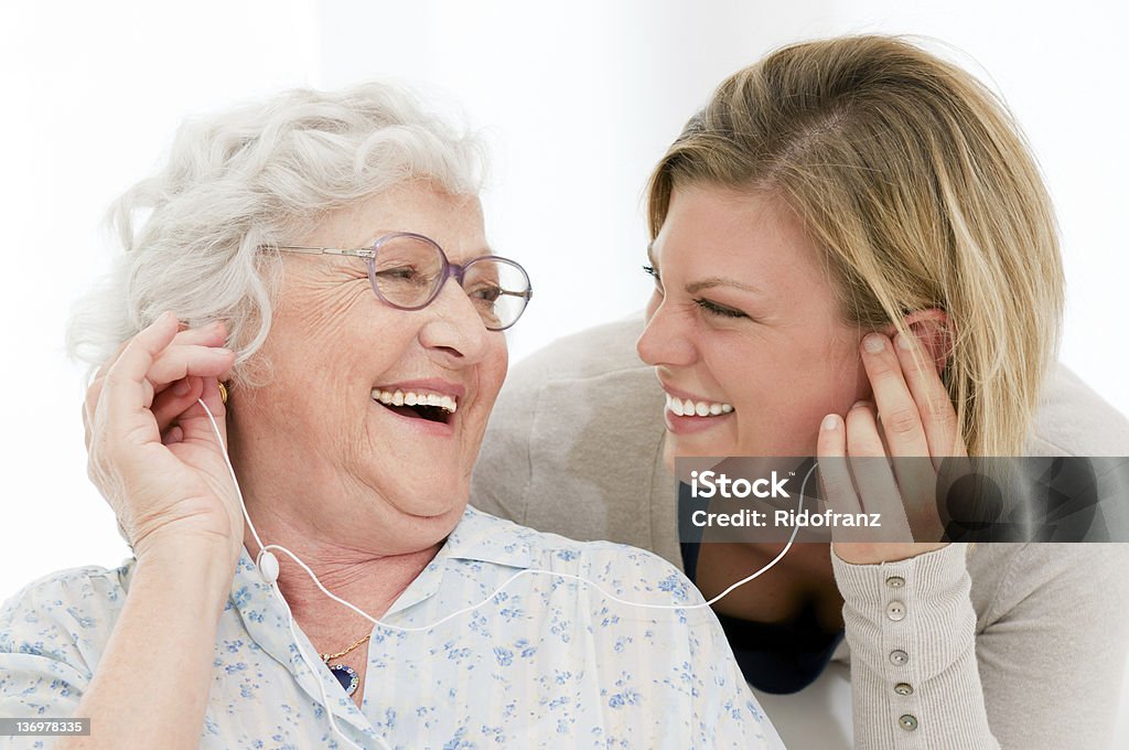 Music fun Excited grandmother listening music together with her granddaughter at home. Senior Adult Stock Photo