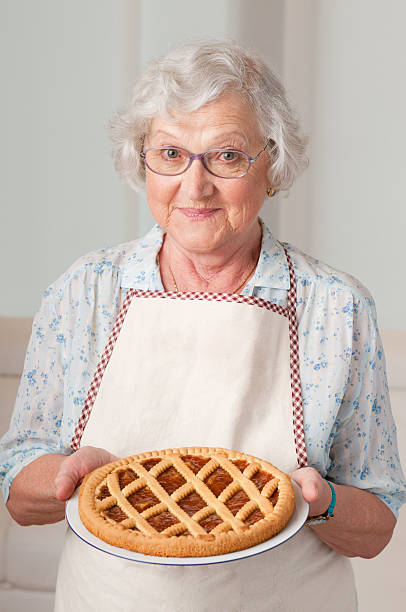 Senior lady with homemade cake Happy smiling senior woman showing her apricot tart. only senior women stock pictures, royalty-free photos & images