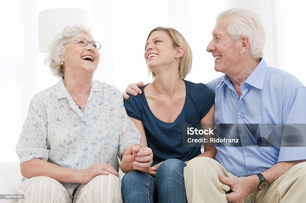 Smiling granddaughter with grandparents Happy smiling girl staying together with her grandparents at home. Senior Couple Stock Photo