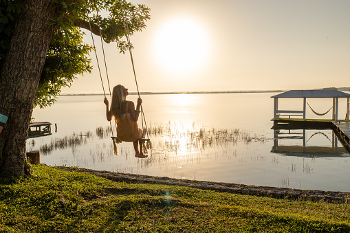 Rear view of woman swinging and relaxing by the lagoon in Mexico.