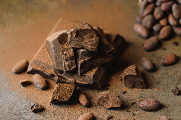 istock Pieces of dark chocolate with cocoa beans on brown background. 1369785429