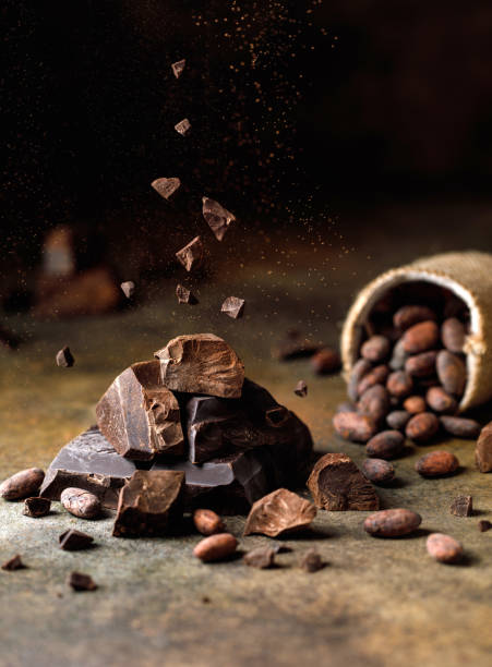 istock Pieces of dark chocolate with cocoa beans on brown background. 1369785444