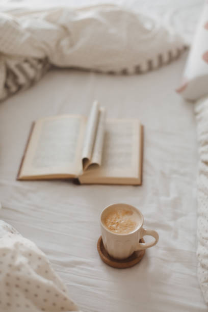 istock Cozy morning composition with a coffee cup and a book with pages folded into a heart shape in bed 1369787947