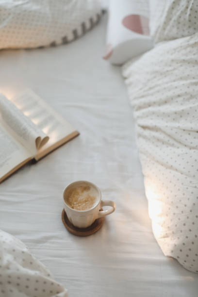 istock Cozy morning composition with a coffee cup and a book with pages folded into a heart shape in bed 1369788689