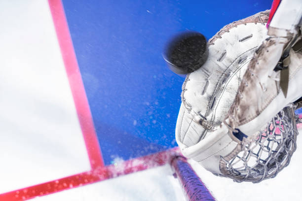 an overhead close-up view of an ice hockey puck about to be caught by goalie’s glove in motion - ice hockey hockey puck playing shooting at goal imagens e fotografias de stock