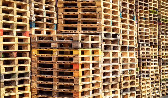 Multiple stacks of wooden pallets to be reused for industrial freight shipping.