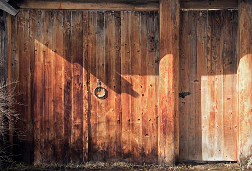 Old wooden gate with a metal handle. Dark orange wood background.