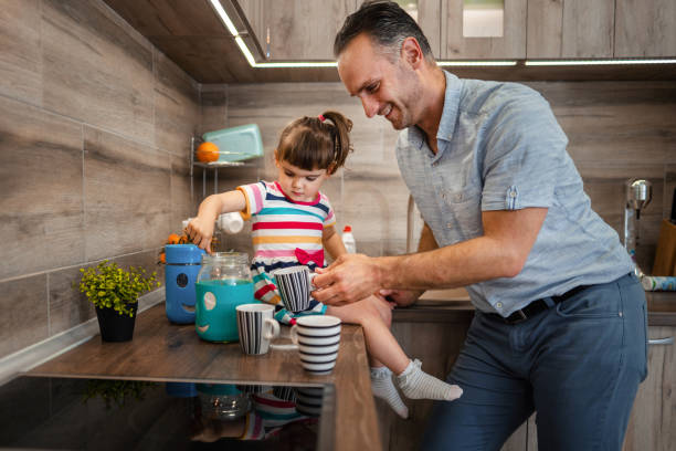 istock Cute little girl watching her father making coffee in the kitchen 1369792462