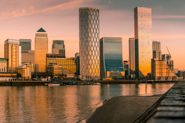 View of Canary Wharf skyscrapers from the river side, lit by the setting sun, London, UK.