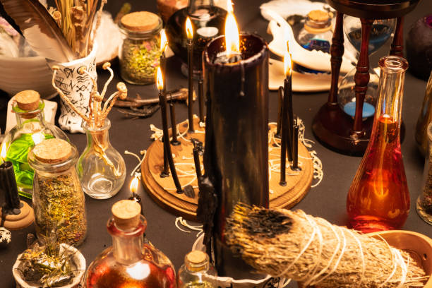 istock Witchcraft still life with black burning candles selective focus. Esoteric gothic and occult witch ritual for Halloween. Various magic objects and ceremony arrangement. Gothic Halloween. 1369795313