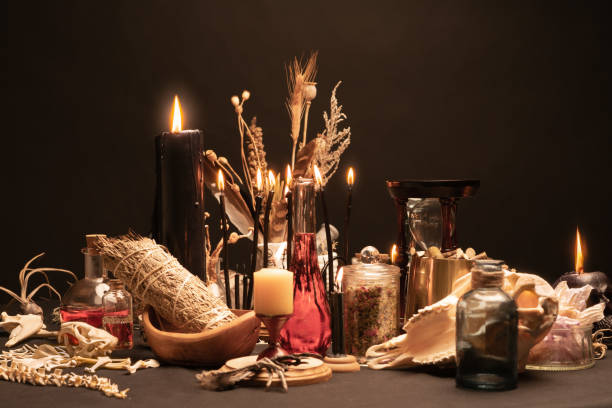 istock Occult and esoteric witch doctor still life. Halloween with magic objects. Black candles, goat skull, teeth, and potions vials with sage, chickens feet, sand clock. Mystic witchery with weeds. 1369795768