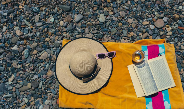 istock Summer holiday concept at seaside with bag, towel, hat and a book 1369797651