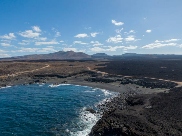 вулканический пляж лас-мальвас на испанском острове лансароте - lanzarote bay canary islands beach стоковые фото и изображения