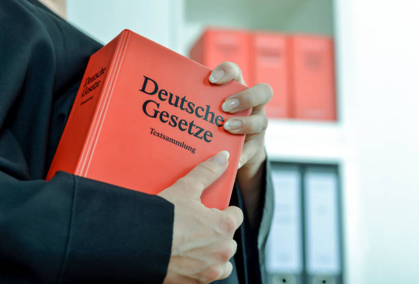 Concept lawyer, court and trial: Detail of a female Attorney in black robe with German law books in hand in her office. The German text on the book means "German Laws Text Collection", selective focus legal defense photos stock pictures, royalty-free photos & images