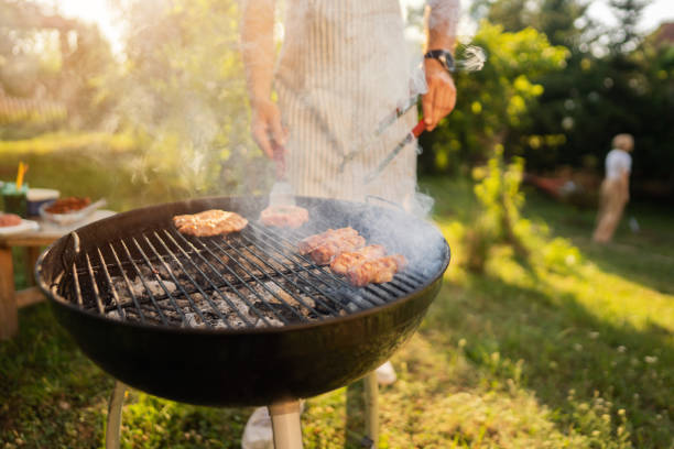 istock Unrecognizable men preparing the beef burger and chicken breast on the BBQ grill 1369805157
