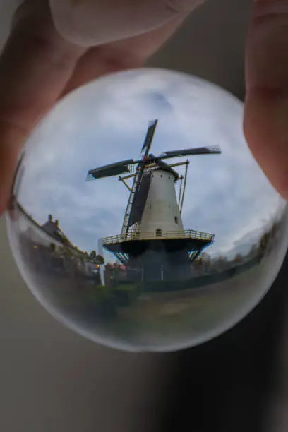 Romantic old Dutch windmill seen in a lensball at a cloudy day