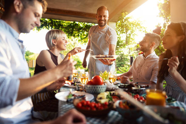 istock Party host a chef, serving to his friends a BBQ, during summer brunch 1369806442
