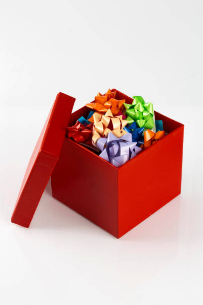 istock Colorful gift bows decorations and packaging materials in red gift box. Vertical close-up, isolated on white background. 1369806736