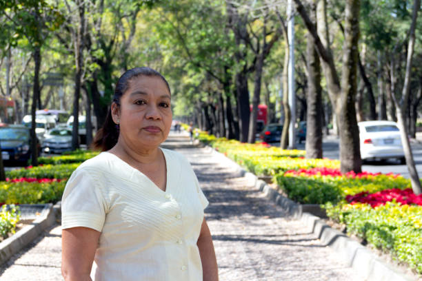 Mature Mexican woman looking at camera, standing on city streets. Latina woman looking at camera. serious attitude.