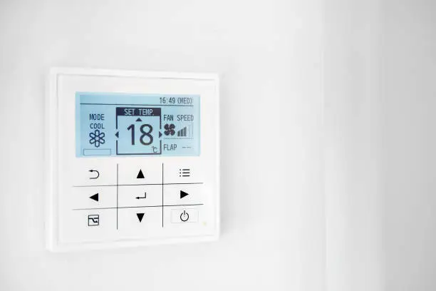 Mounted on wall, climate control show 18 degrees indoor, remote air-conditioner inside smart home close up view, no people. Modern tech, comfort living concept