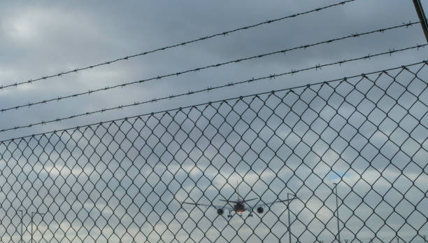istock Plane flys behind Airport Fence 1369811116