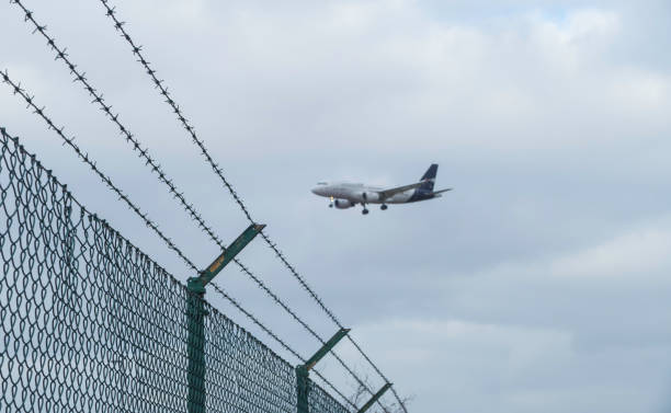 istock Airplane flying over Airport Fence 1369811302