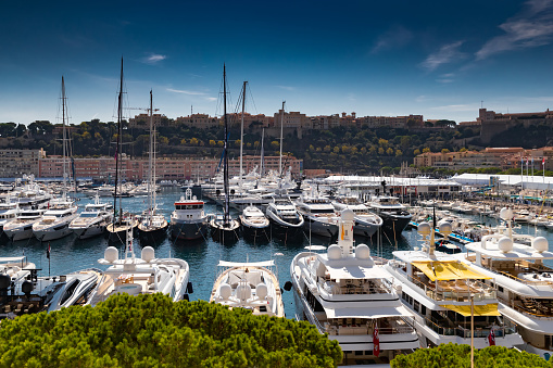 A lot of huge yachts are in port Hercule of Monaco at sunny day, Monte Carlo, many small boats are on background, interiors of motor boat, chilling zone of megayachts, sun reflections on glossy boards. High quality photo
