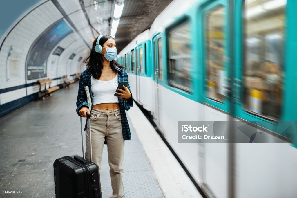 Young budget traveler enjoying city break in Paris in summer and wearing protective face mask Beautiful millennial woman in Paris, traveling during pandemic Subway Stock Photo