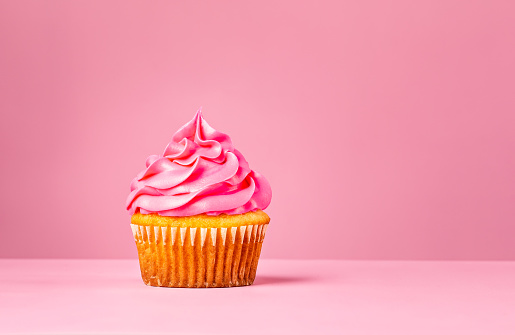 Pink Cupcake with buttercream frosting over a pink background.
