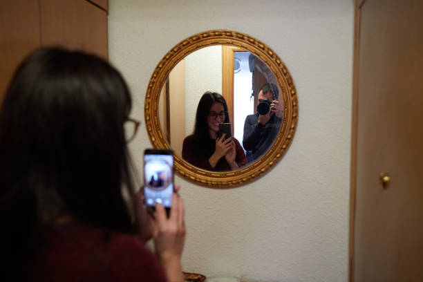 istock Smiling girl taking a selfie with a mirror while an anonymous boy takes her picture 1369813032