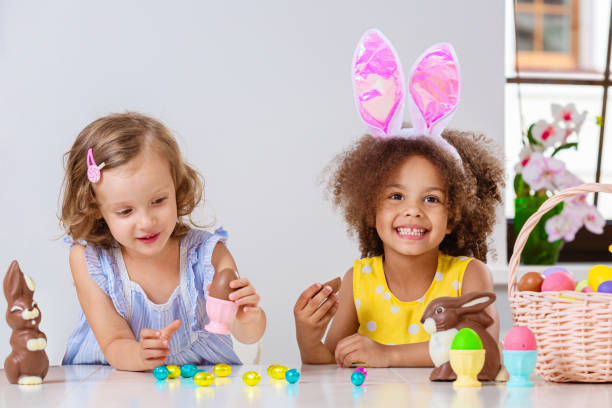 istock Black and White children in bright clothes eating Easter eggs 1369813080