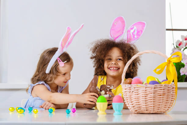 ragazza in bianco e nero in orecchie da coniglio rosa gioca con il coniglietto di cioccolato di pasqua - easter easter egg child chocolate foto e immagini stock