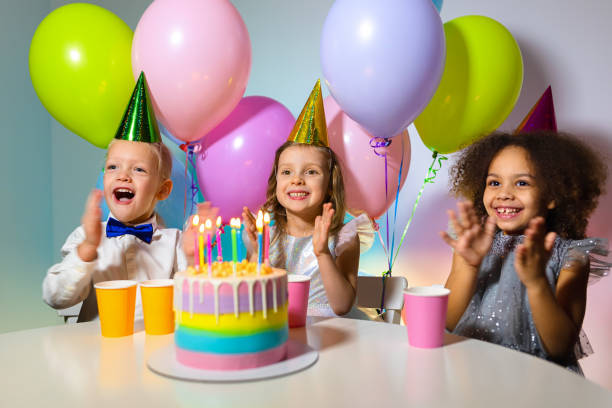 istock happy kids with cake and balloons clapping their hands 1369813094