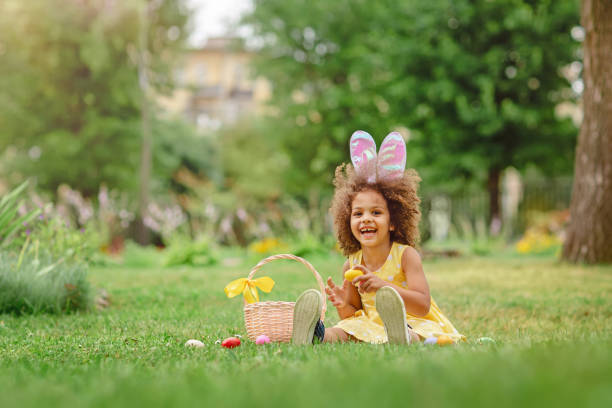 istock Little Black girl wtfring bunny ears gathering Easter eggs 1369813110