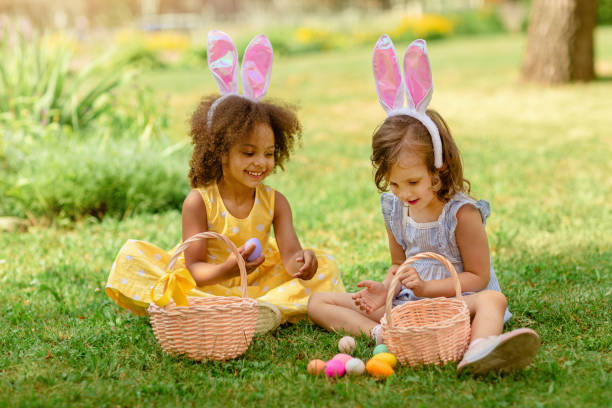 children find and pick up multicolored egg on easter egg hunt - rabbit hunting imagens e fotografias de stock