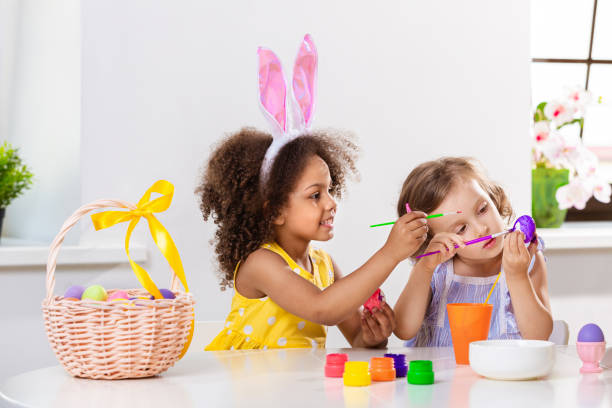 istock Two girls paint Easter eggs for holiday at home 1369813117