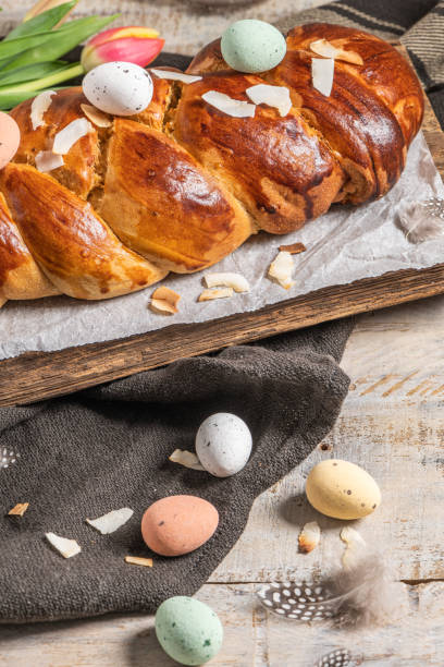 istock Portuguese traditional Easter cake. Folar with eggs on easter table. Blossom tulips, colorful painted eggs and feathers 1369813831