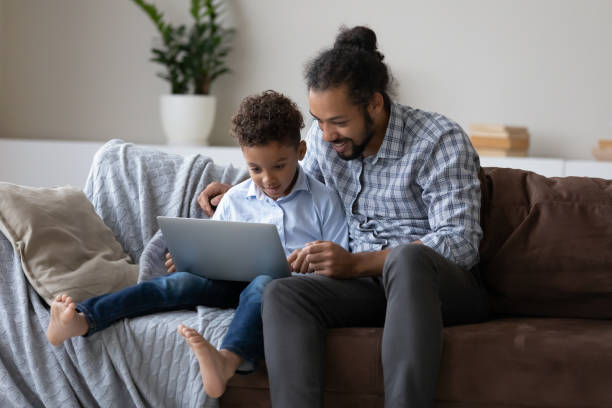 istock Happy young Black dad and 7s son boy using laptop 1369813902