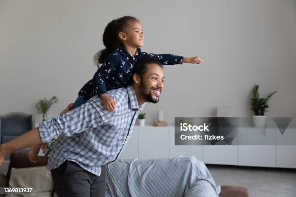 Happy African American Dad Piggybacking Excited Proud Daughter Kid Stock Photo - Download Image Now