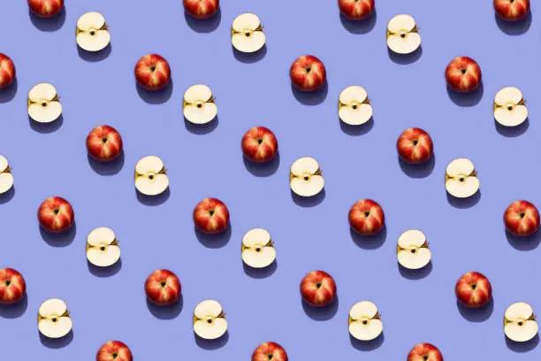 Photo of Fruit pattern red apple on trendy purple background. Violet and red colors background from fruity apple. Demonstrating the very peri, colors of 2022.