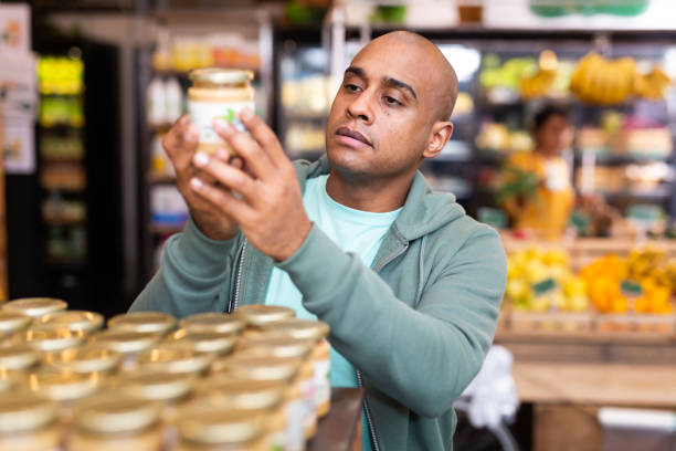 istock Man reading jar contents on label while shopping in supermarket 1369815422