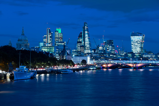London at dusk, view across Thames River with boats, Blackfriars Bridge, St Paul's Cathedral and financial buildings in the background, United Kingdom.