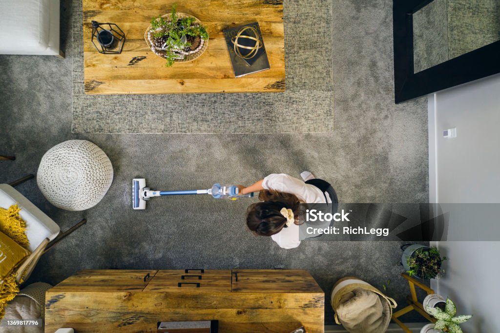 Professional Housecleaner at Work A professional housecleaner at work cleaning a home. Housework Stock Photo