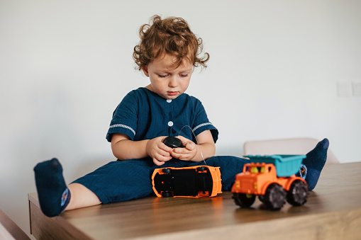 Cute boy playing with toy cars at home