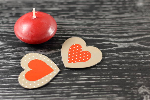 a red candle and heart on a table stock photo