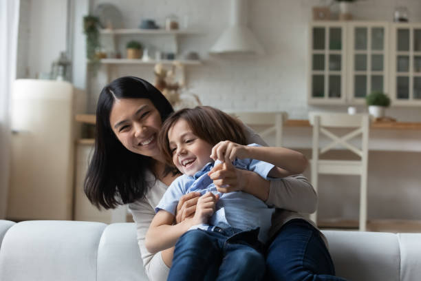istock Cheerful Asian babysitter tickling little cute boy 1369822200
